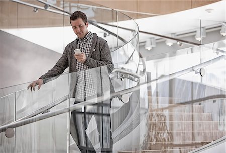 simsearch:6118-08351860,k - A man standing on spiral stairs checking his smart phone. Stock Photo - Premium Royalty-Free, Code: 6118-08351959