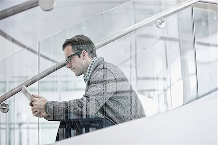 A man seated on steps using a digital tablet. Stock Photo - Premium Royalty-Free, Code: 6118-08351961