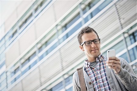 simsearch:6118-08351860,k - A man in a checked shirt with open collar holding his smart phone. Stock Photo - Premium Royalty-Free, Code: 6118-08351977