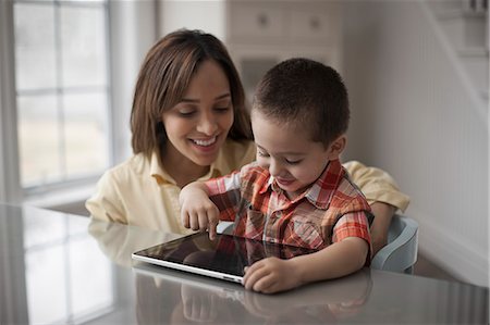 simsearch:6108-05867616,k - A mother and child looking at the screen of a digital tablet, the boy touching the screen. Stock Photo - Premium Royalty-Free, Code: 6118-08351994