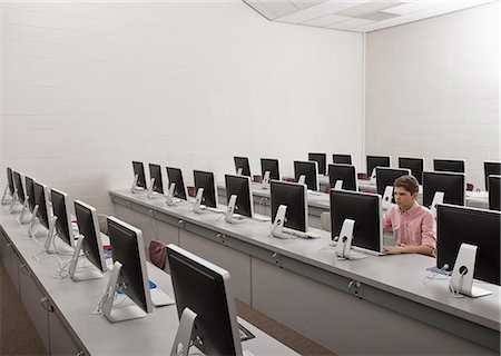 simsearch:6118-08351907,k - A school room, a computer lab with rows of screens and seating. A young person seated working at a terminal. Photographie de stock - Premium Libres de Droits, Code: 6118-08351930