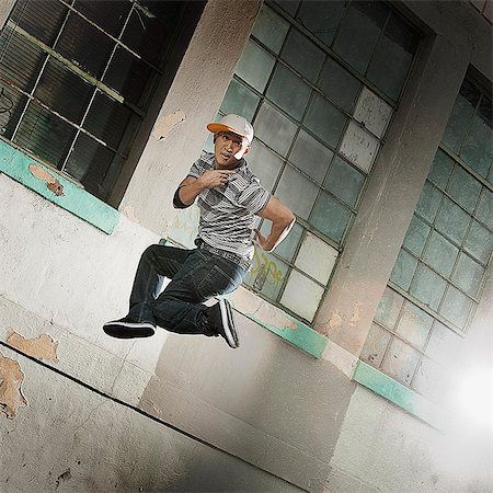 simsearch:6118-08393913,k - A young man breakdancing on a city sidewalk leaping in the air and striking a pose, looking at the camera. Stock Photo - Premium Royalty-Free, Code: 6118-08393896