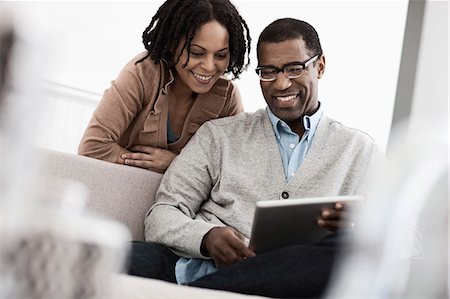 A couple, man and woman seated sharing a digital tablet. Stock Photo - Premium Royalty-Free, Code: 6118-08393948
