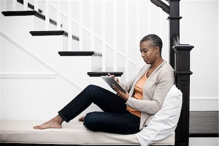 simsearch:6118-07966891,k - A mature woman seated in a hallway using a digital tablet. Photographie de stock - Premium Libres de Droits, Code: 6118-08393919
