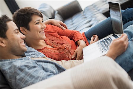 simsearch:6118-07966891,k - A man and woman sitting on a sofa, looking at the screen of a laptop. Photographie de stock - Premium Libres de Droits, Code: 6118-08394046