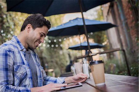 sinceridad - A man sitting at a cafe table outdoors, using his phone. Foto de stock - Sin royalties Premium, Código: 6118-08394078