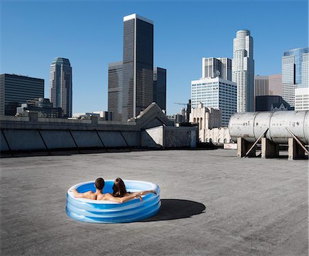 simsearch:6118-08394126,k - A couple, a man and woman sitting in a small inflatable water pool on a city rooftop, cooling down. Foto de stock - Sin royalties Premium, Código: 6118-08394086