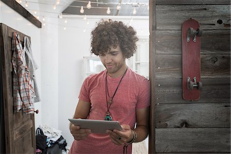 Loft living. A young man standing looking at a digital tablet. Photographie de stock - Premium Libres de Droits, Code: 6118-08394028