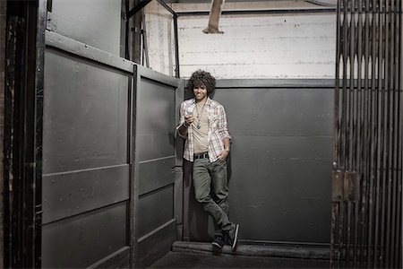 Loft living. A man in a loft elevator checking his phone. Photographie de stock - Premium Libres de Droits, Code: 6118-08394036