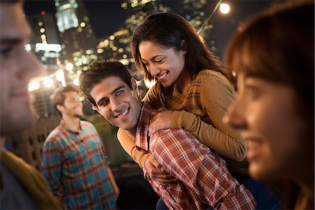 A group of men and women at a rooftop party with a view over the city. Stock Photo - Premium Royalty-Free, Code: 6118-08394132