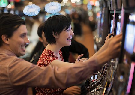 Two people, a young man and woman, playing the slot machines in a casino. Fotografie stock - Premium Royalty-Free, Codice: 6118-08394207