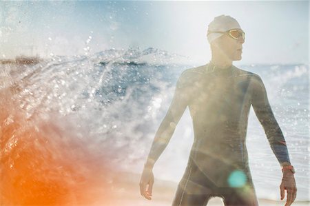 A swimmer in a wet suit standing by the water's edge. Stock Photo - Premium Royalty-Free, Code: 6118-08399558
