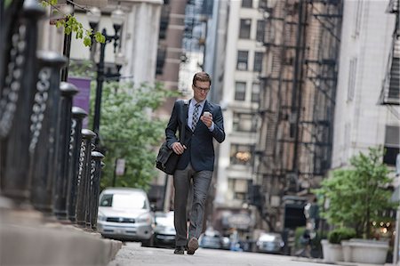 A working day. Businessman in a work suit and tie on a city street checking his smart phone. Foto de stock - Sin royalties Premium, Código: 6118-08399584