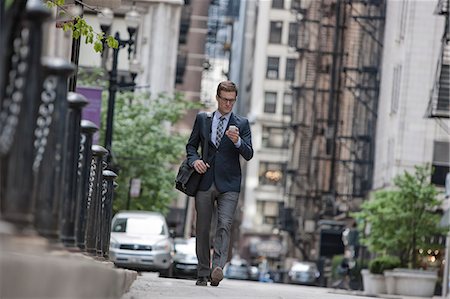 A working day. Businessman in a work suit and tie on a city street checking his smart phone. Stockbilder - Premium RF Lizenzfrei, Bildnummer: 6118-08399584