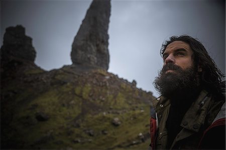 simsearch:6118-09076526,k - A man standing with a backdrop of rock pinnacles on the skyline towering over him, an overcast sky with low cloud. Photographie de stock - Premium Libres de Droits, Code: 6118-08399667