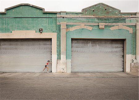 A woman in running gear, crop top and shorts, stretching her body and preparing for a run, or cooling down after exercise. Stock Photo - Premium Royalty-Free, Code: 6118-08399606