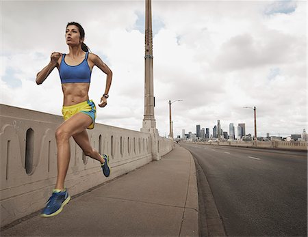 simsearch:6118-08399616,k - A woman running along an urban road pumping her arms and stretching her legs. Stockbilder - Premium RF Lizenzfrei, Bildnummer: 6118-08399620