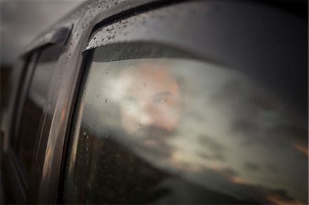 A man sitting in a car looking out. Reflections of the sunset sky on the window. Foto de stock - Sin royalties Premium, Código: 6118-08399707