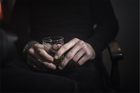 A man's hands holding a glass of whisky. Fotografie stock - Premium Royalty-Free, Codice: 6118-08399704