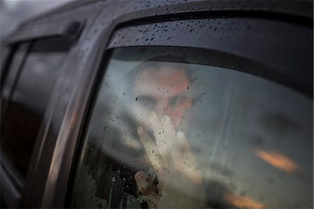 simsearch:6118-08399708,k - A man sitting in a car looking out. Reflections of the sunset sky on the window. Stockbilder - Premium RF Lizenzfrei, Bildnummer: 6118-08399706