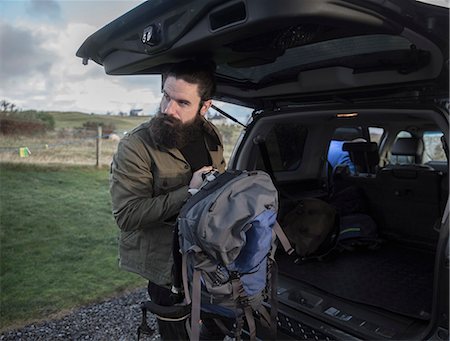 A man carrying a rucksack standing by an open car boot. Photographie de stock - Premium Libres de Droits, Code: 6118-08399709