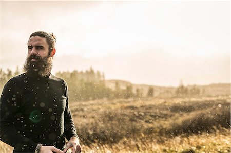 simsearch:6118-08399699,k - A man standing in sunlit open country in winter. Foto de stock - Royalty Free Premium, Número: 6118-08399714