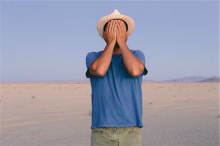 simsearch:6118-08860601,k - A man in an open desert landscape covering his face with his hands. Foto de stock - Sin royalties Premium, Código: 6118-08313765