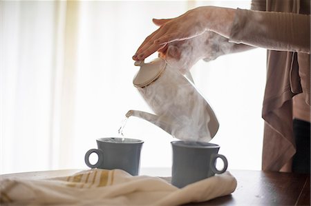 Close up of a woman pouring hot water from a coffee pot into a mug. Stock Photo - Premium Royalty-Free, Code: 6118-08313714