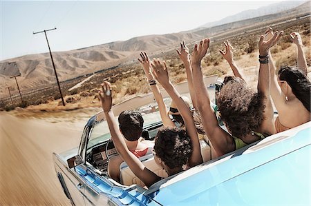 simsearch:6118-08488203,k - A group of friends in a pale blue convertible on the open road, driving across a dry flat plain surrounded by mountains. Stock Photo - Premium Royalty-Free, Code: 6118-08488173
