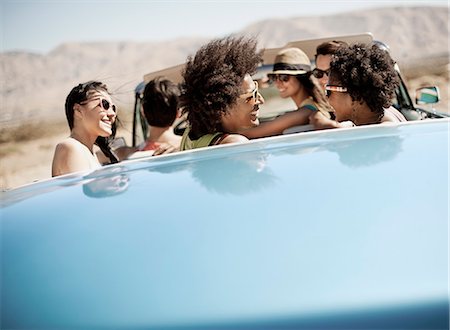 simsearch:6118-08488203,k - A group of friends in a pale blue convertible on the open road, driving across a dry flat plain surrounded by mountains. Stock Photo - Premium Royalty-Free, Code: 6118-08488170