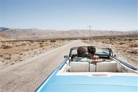 simsearch:6118-08991581,k - A young couple, man and woman in a pale blue convertible on the open road Stock Photo - Premium Royalty-Free, Code: 6118-08488186