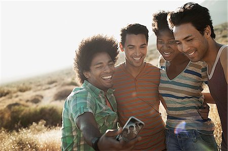 simsearch:6118-08488203,k - A group of friends, men and women, heads together posing for a selfy in the heat of the day. Stock Photo - Premium Royalty-Free, Code: 6118-08488109