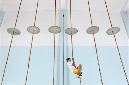 simsearch:6118-08351907,k - A boy climbing up a rope at the gym. Fotografie stock - Premium Royalty-Free, Codice: 6118-08488235