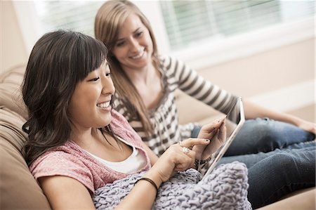 simsearch:6118-07966891,k - Two women seated on a sofa looking at a digital tablet. Photographie de stock - Premium Libres de Droits, Code: 6118-08488382