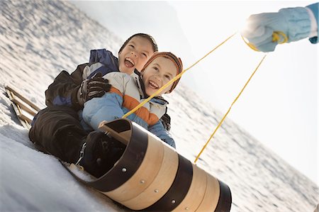 A person pulling two children along on a sledge. Stock Photo - Premium Royalty-Free, Code: 6118-08488397