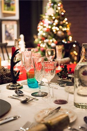 A table laid for a Christmas meal, with silver and crystal glasses and a Christmas tree in the background. Foto de stock - Royalty Free Premium, Número: 6118-08488463