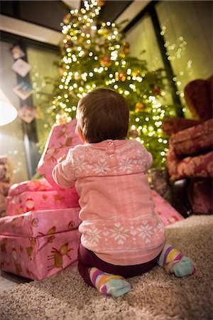 A toddler beside a pile of presents under a Christmas tree. Foto de stock - Sin royalties Premium, Código: 6118-08488461