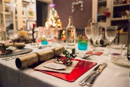 porta-cartões - A table laid for a Christmas meal, with silver and crystal glasses and a Christmas tree in the background. Foto de stock - Royalty Free Premium, Número: 6118-08488464