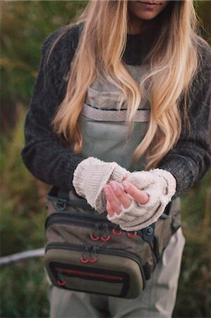 simsearch:6118-08023790,k - A woman with long blonde hair putting on woollen fingerless mittens. Stock Photo - Premium Royalty-Free, Code: 6118-08488411