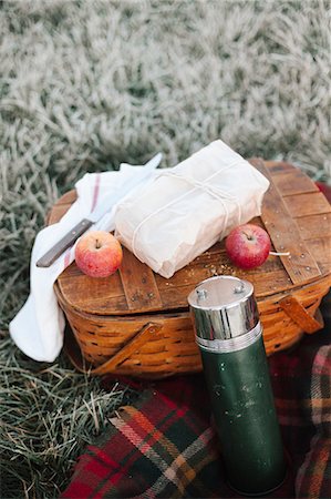 fruit winter basket - A winter picnic, apples and a wrapped cake by a fishing basket on a rug. Stock Photo - Premium Royalty-Free, Code: 6118-08488423