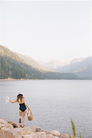 simsearch:6118-08088612,k - A woman in a swimsuit carrying a basket along the shore of a mountain lake. Stock Photo - Premium Royalty-Free, Code: 6118-08488436