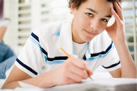 simsearch:6118-08660001,k - A boy lying on his front writing in a school book. Stock Photo - Premium Royalty-Free, Code: 6118-08521656