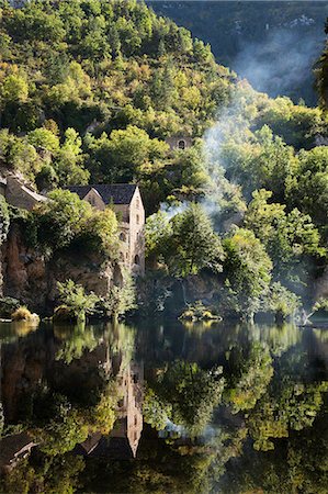 simsearch:6113-07242277,k - Houses on a steep hillside, reflected on the water of a river. Woodland, and a thin stream of rising wood smoke. Stock Photo - Premium Royalty-Free, Code: 6118-08521683