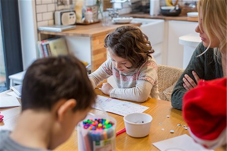 Three children and an adult woman at a table, drawing and writing cards and letters to Santa. Foto de stock - Sin royalties Premium, Código: 6118-08521746