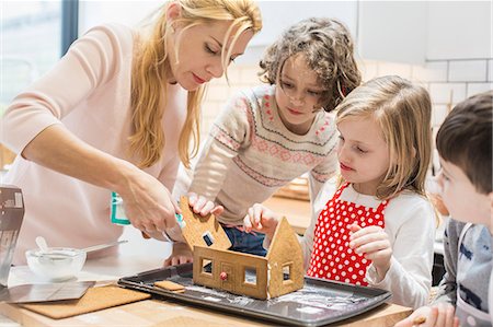 family and christmas and four people - A woman and three children creating a baked gingerbread house. Stock Photo - Premium Royalty-Free, Code: 6118-08521750