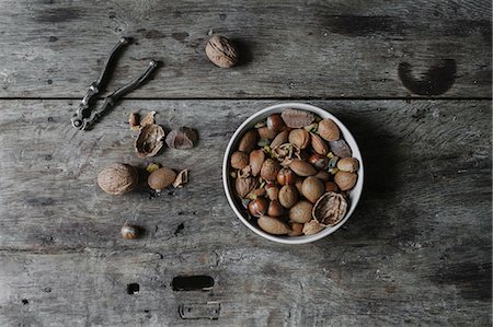 simsearch:6118-08521776,k - A bowl of mixed nuts, shells and a nutcracker on a table. Photographie de stock - Premium Libres de Droits, Code: 6118-08521777