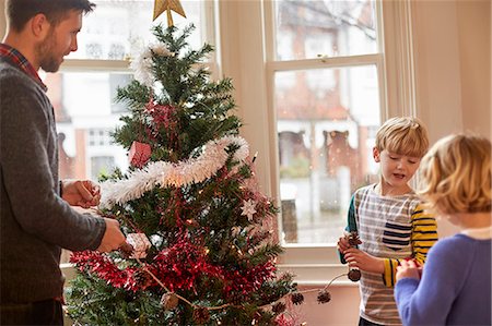 A father and two children decorating a Christmas tree at home. Stock Photo - Premium Royalty-Free, Code: 6118-08521717
