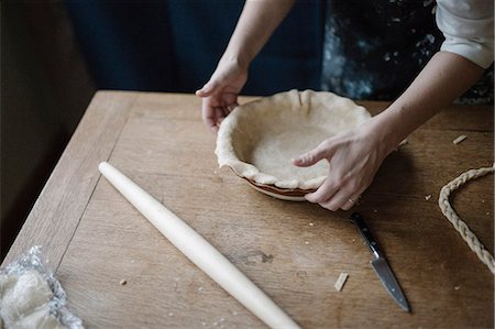 A woman working smoothing the edge of a pastry case lining a pie dish. Photographie de stock - Premium Libres de Droits, Code: 6118-08521860