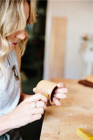 simsearch:6118-08659688,k - A woman in a workshop using a slab of wax to oil a small wood turned cup or bowl. Stockbilder - Premium RF Lizenzfrei, Bildnummer: 6118-08521874