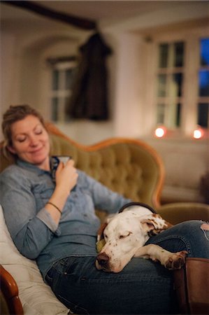 se reposer - A woman seated on a sofa with a large dog with his head on her lap. Photographie de stock - Premium Libres de Droits, Code: 6118-08521830